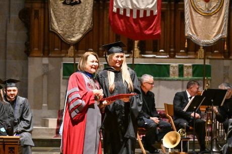 An image of Muhlenberg student Alexandra Caporusso and Muhlenberg President Kathy Harring shaking hands and exchanging a diploma at commencement.